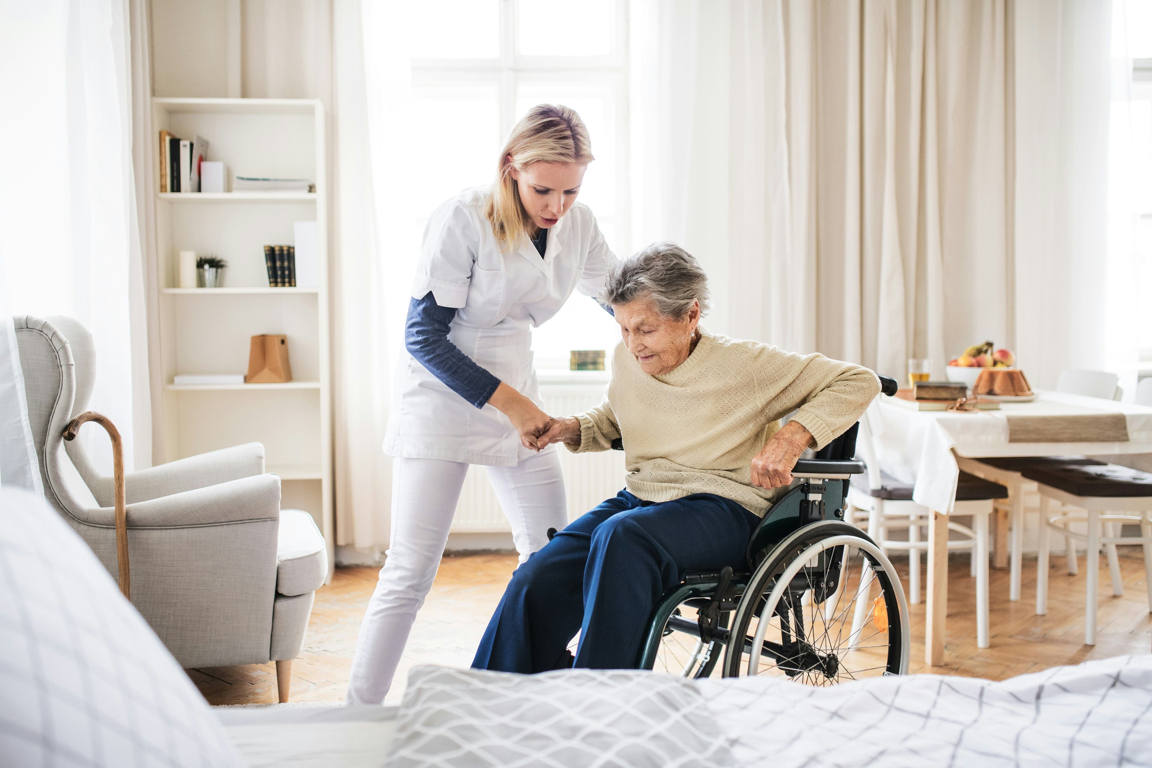 Home care aide helping senior into bed